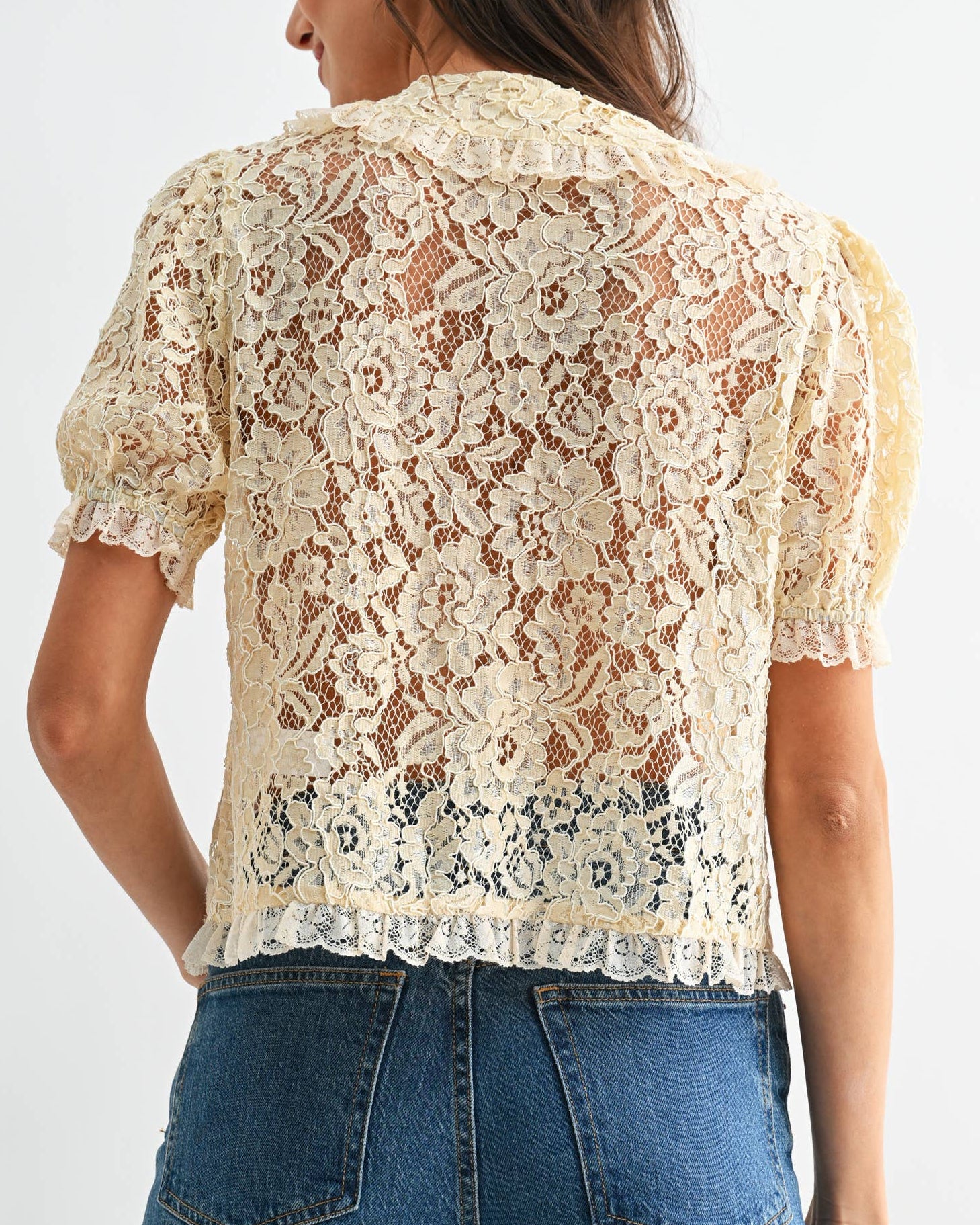 Woman wearing a lace top and blue jeans on a white background