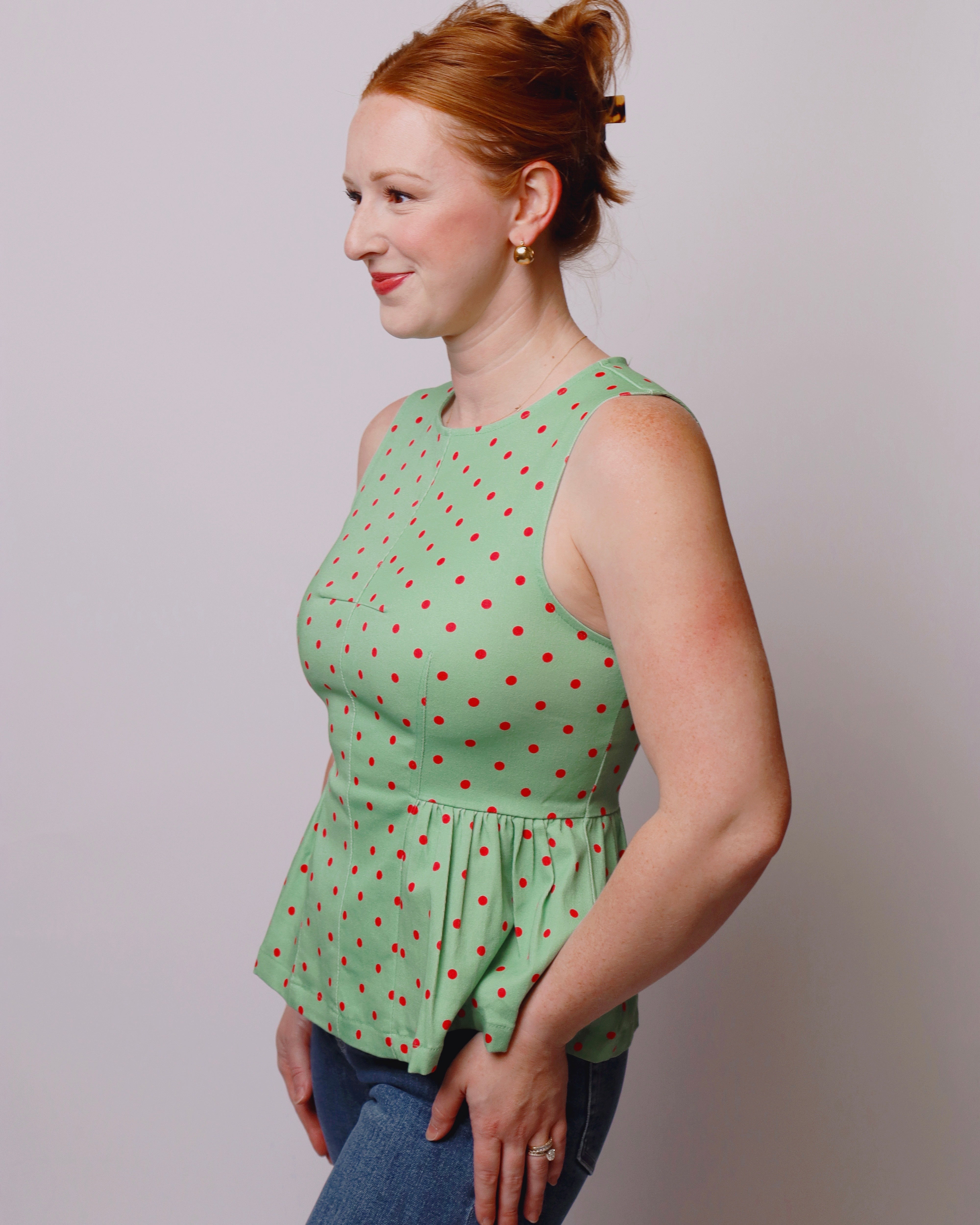 Woman wearing a green polka dot top against a plain background