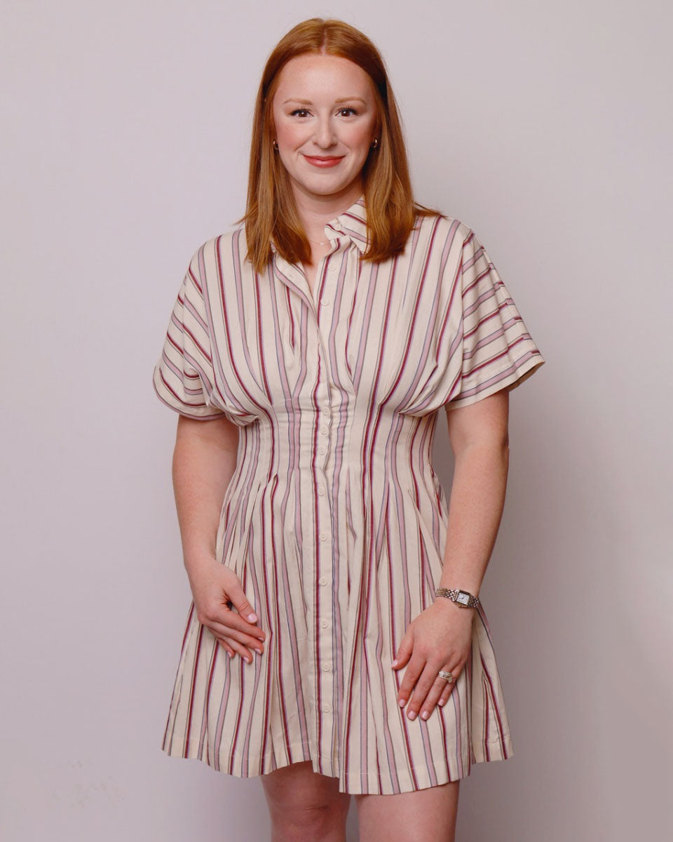 Woman wearing a striped dress against a plain background