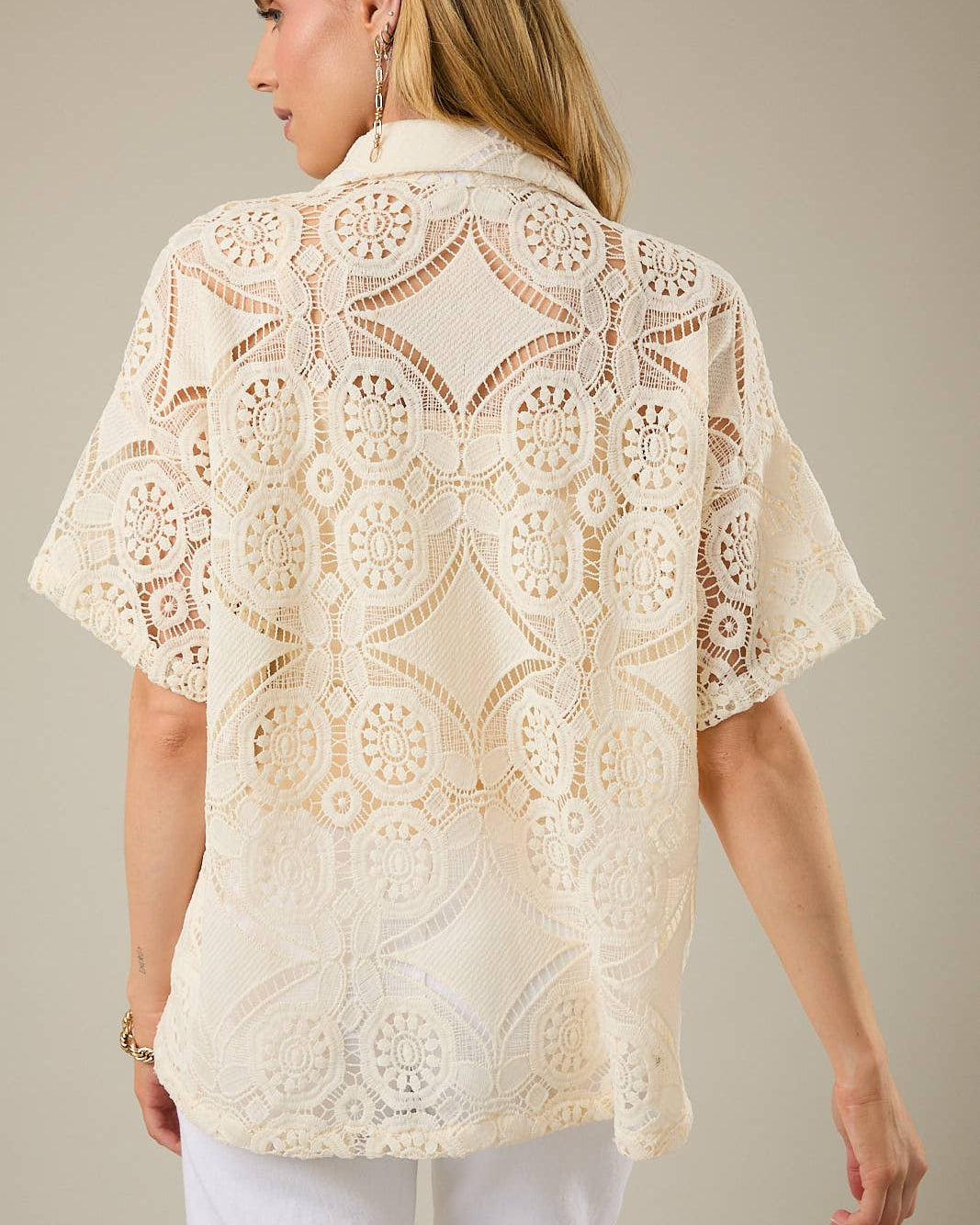 Woman wearing a beige lace blouse against a neutral background