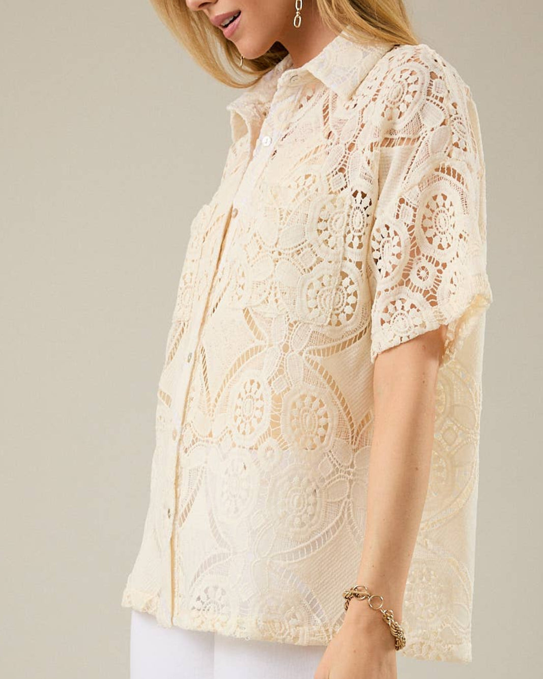 Woman wearing a beige lace blouse against a plain background