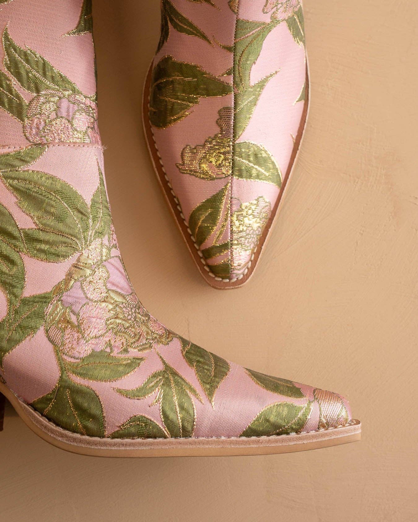 Pink shoes with green leaf pattern on a beige background