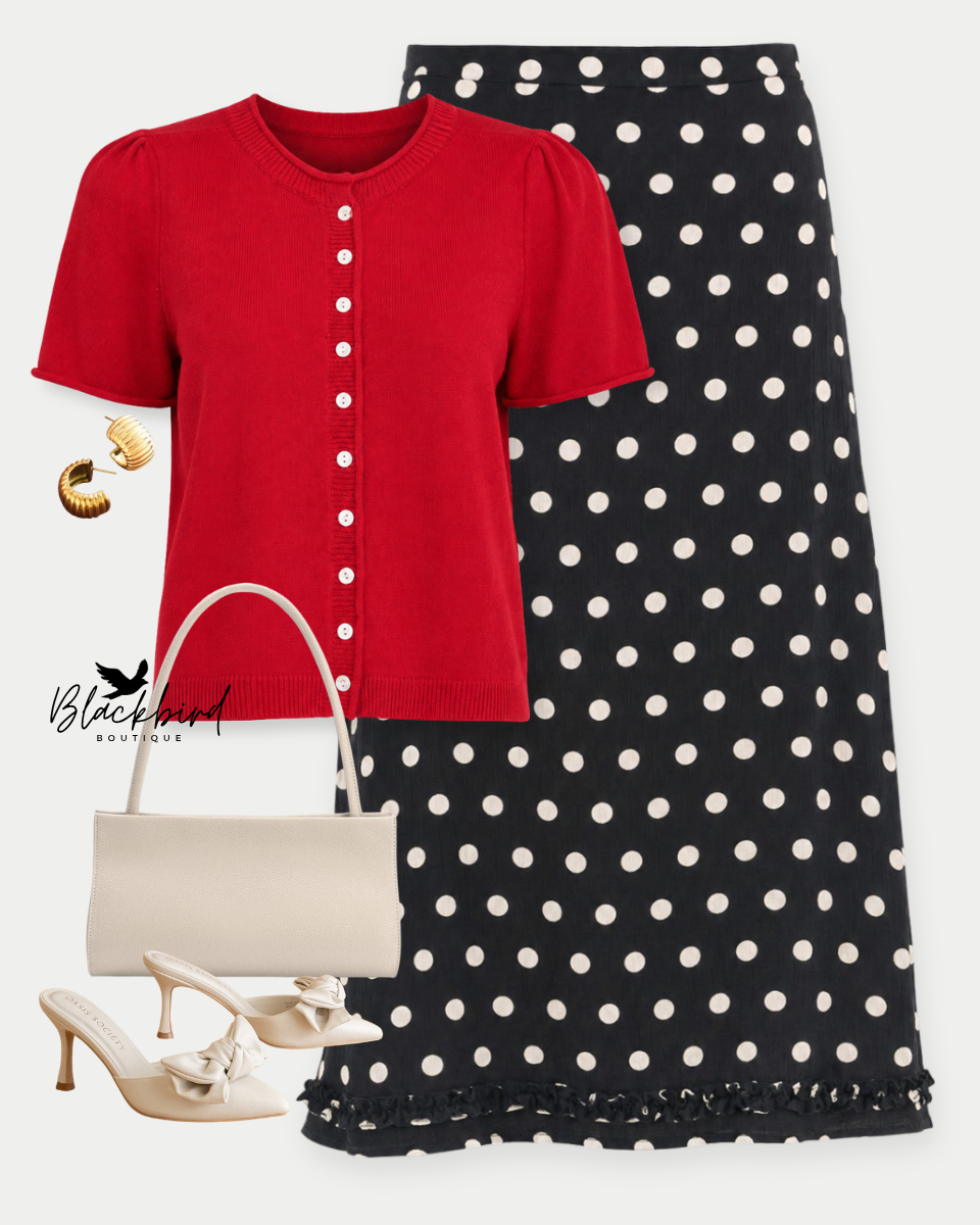 A styled outfit flat-lay featuring a red short-sleeve button-front top, a black midi skirt with white polka dots, cream-colored mule heels, a cream handbag, and gold hoop earrings on a light gray background.