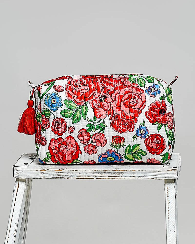 Floral patterned bag with tassels on a white stool against a gray background