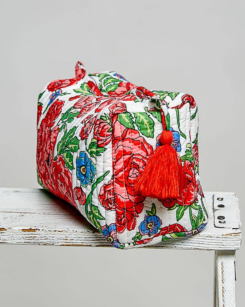 Floral-patterned pouch with a red tassel on a white surface
