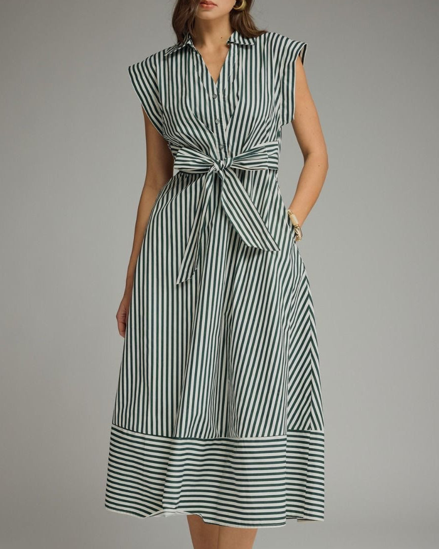A woman modeling a capsleeve midi dress with vertical green and white stripes, a collared neckline, and a self-tie waist, photographed against a neutral studio background.