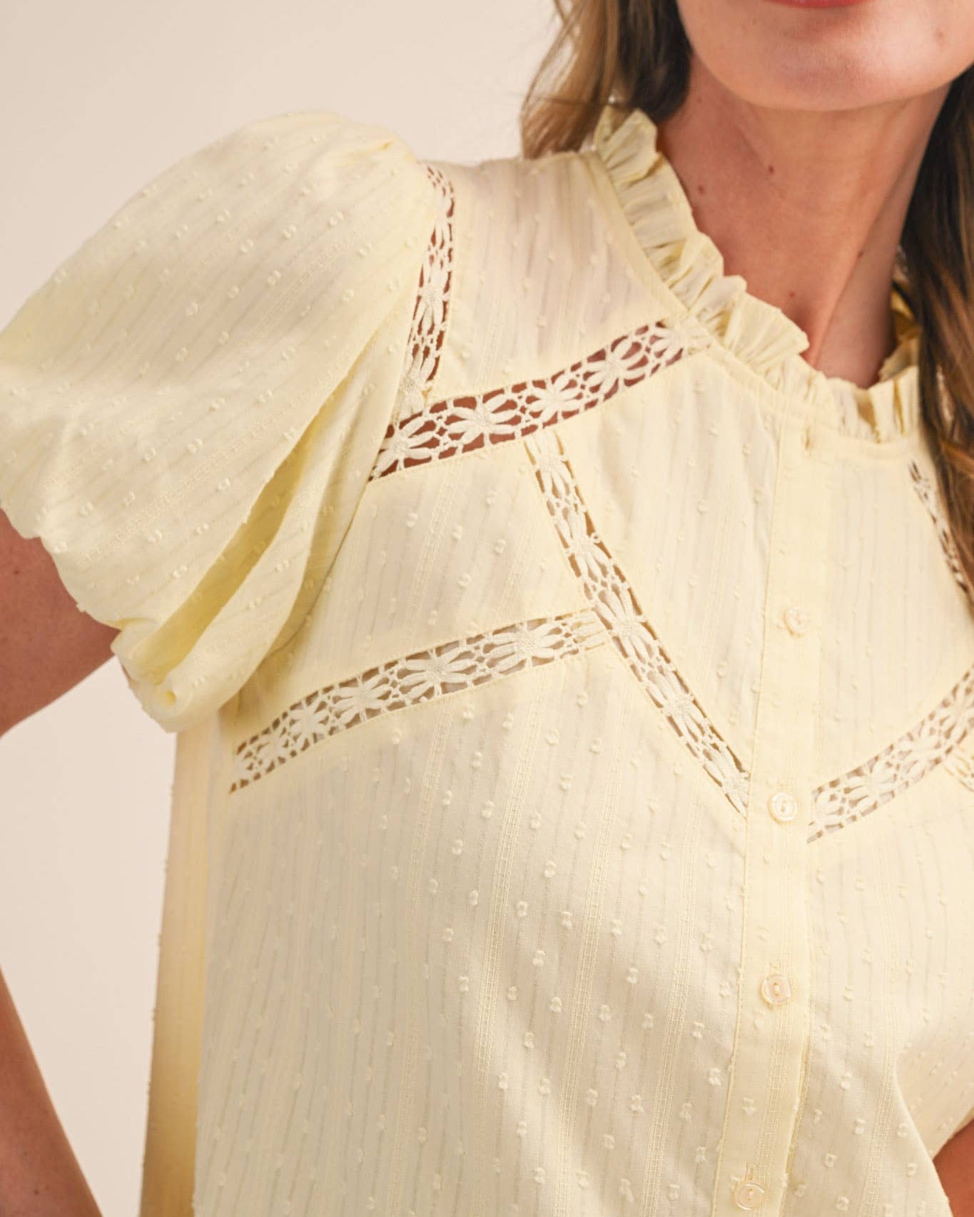 Close-up of a woman wearing a light yellow blouse with lace details.