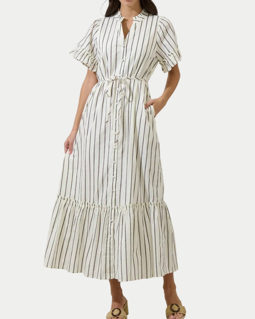 Woman wearing a white dress with black stripes against a plain background