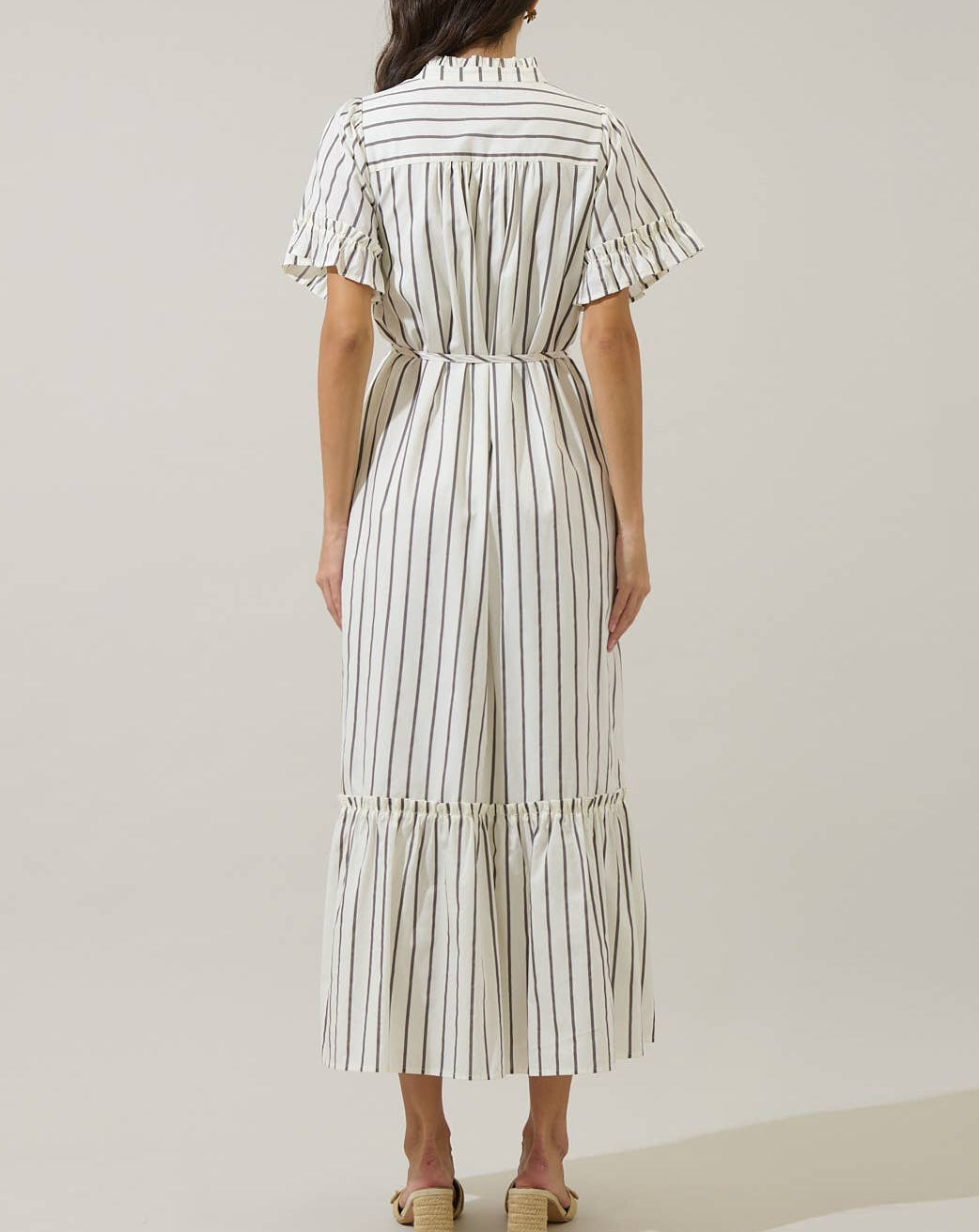 Woman wearing a white and black striped dress on a plain background