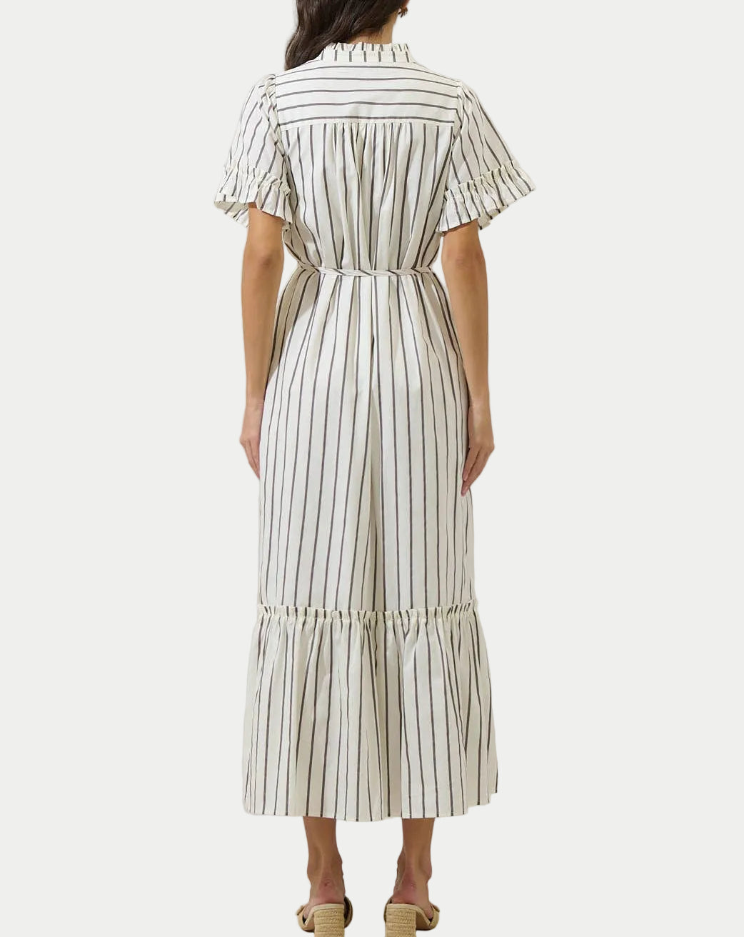 Woman wearing a white and black striped dress on a plain background