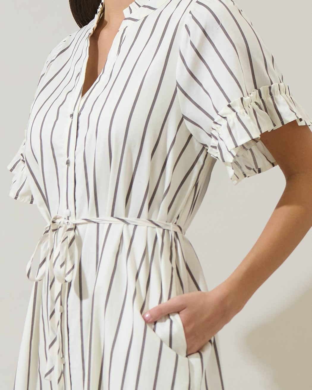 Woman wearing a white and black striped dress with a plain background