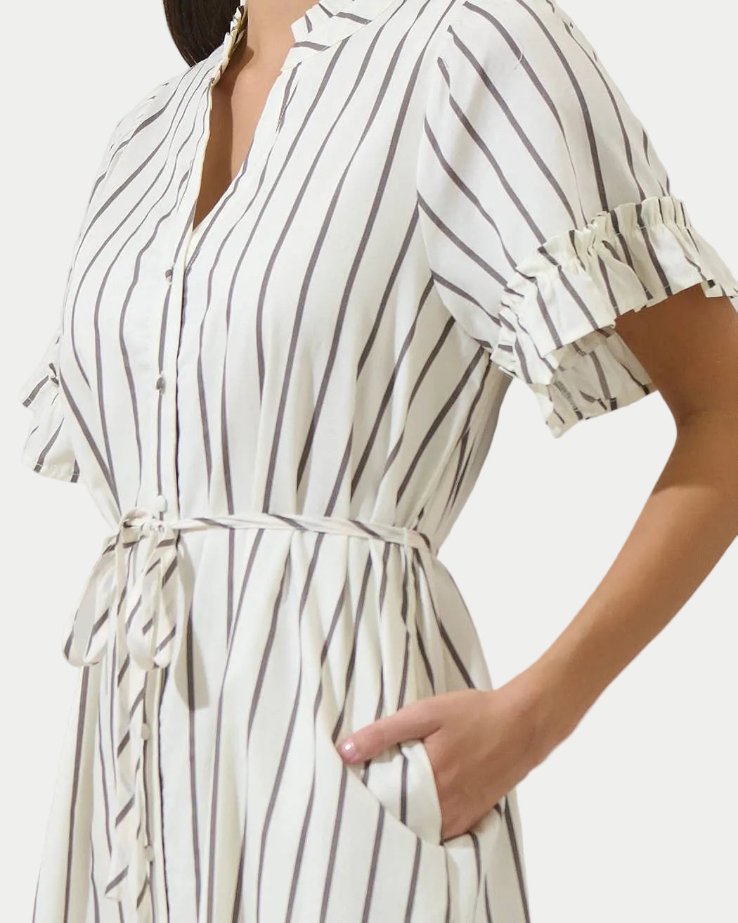 Woman wearing a white and black striped dress with a plain background