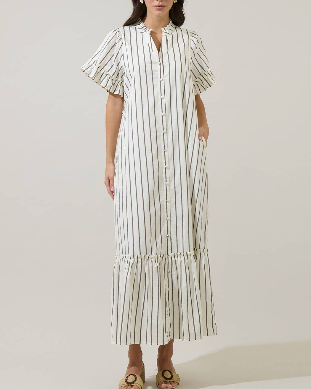 Woman wearing a long, white dress with black stripes against a plain background