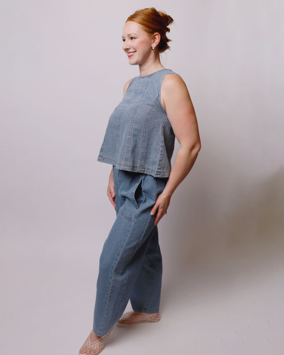 Woman wearing a blue sleeveless top and wide-leg pants against a plain background