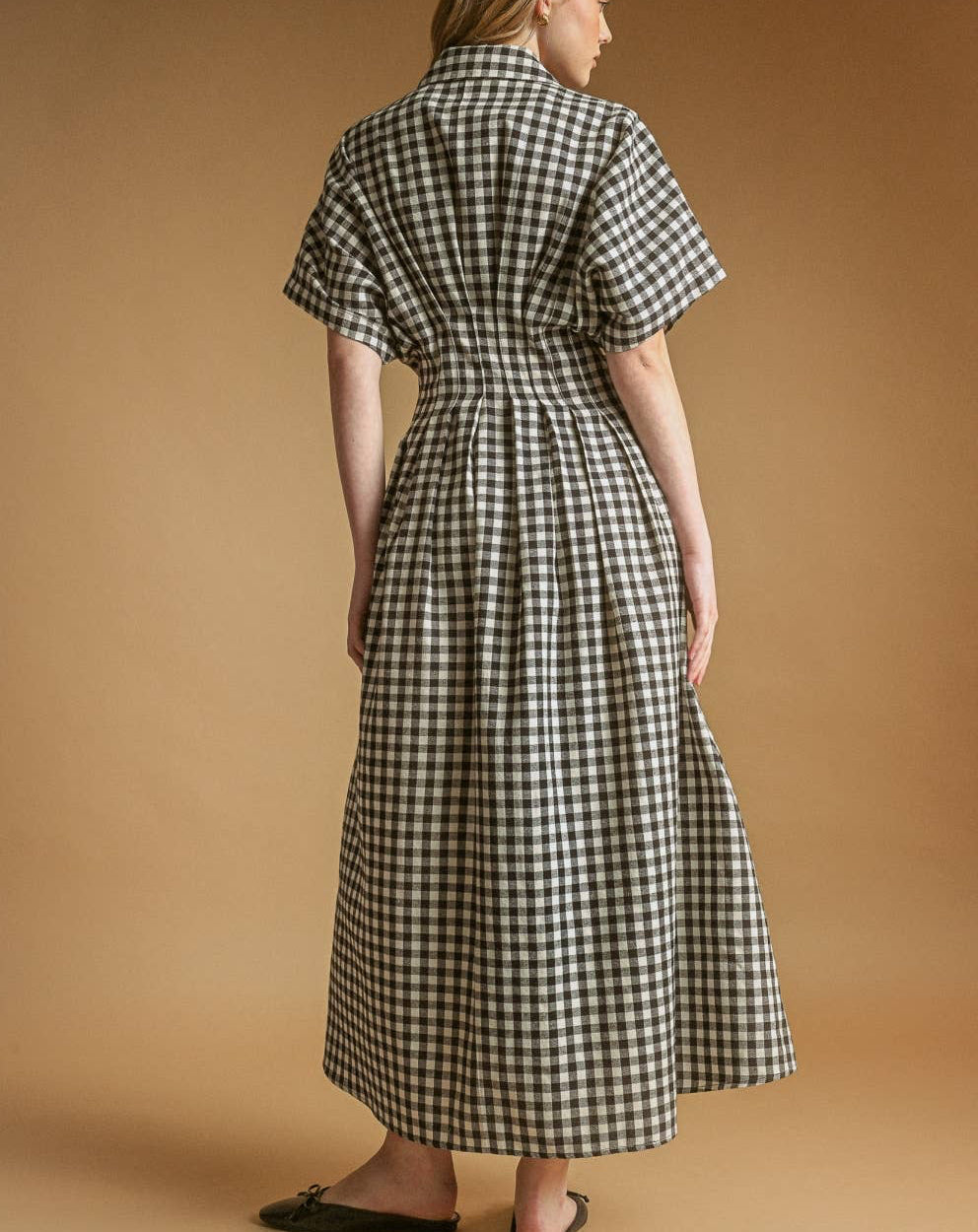 Woman wearing a black and white checkered dress against a brown background
