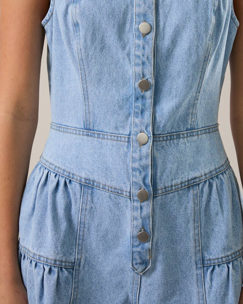 Light blue denim romper worn by a person on a neutral background