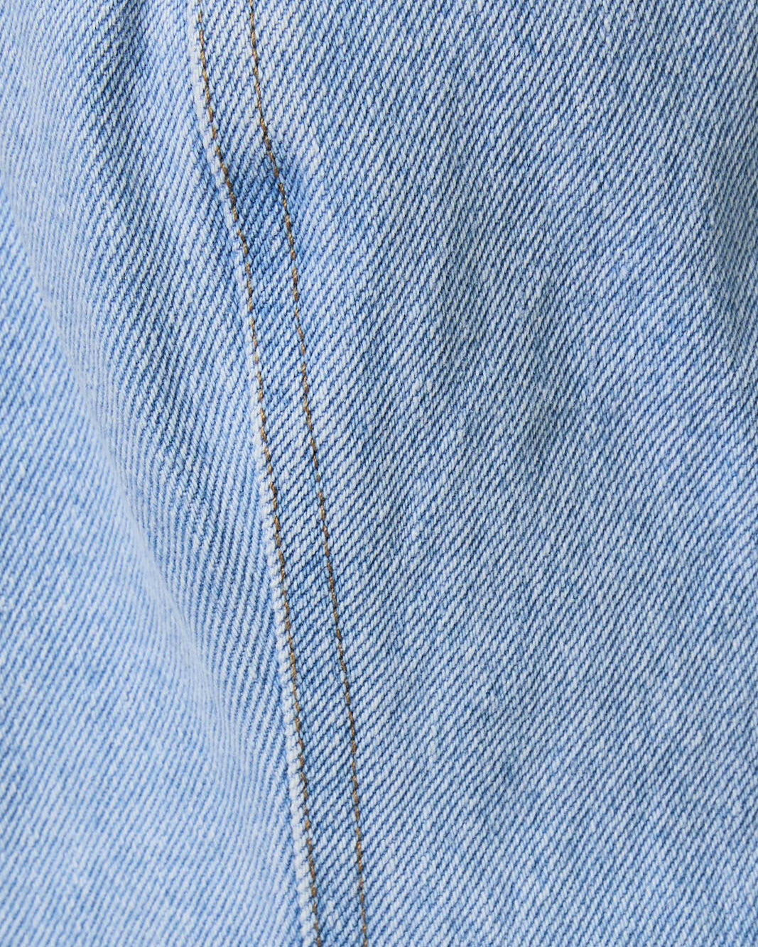 Close-up of blue denim fabric with a visible seam.