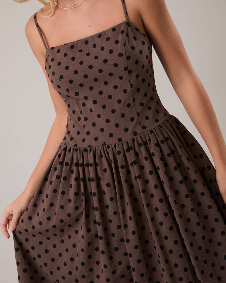 Woman wearing a brown polka dot dress against a plain background