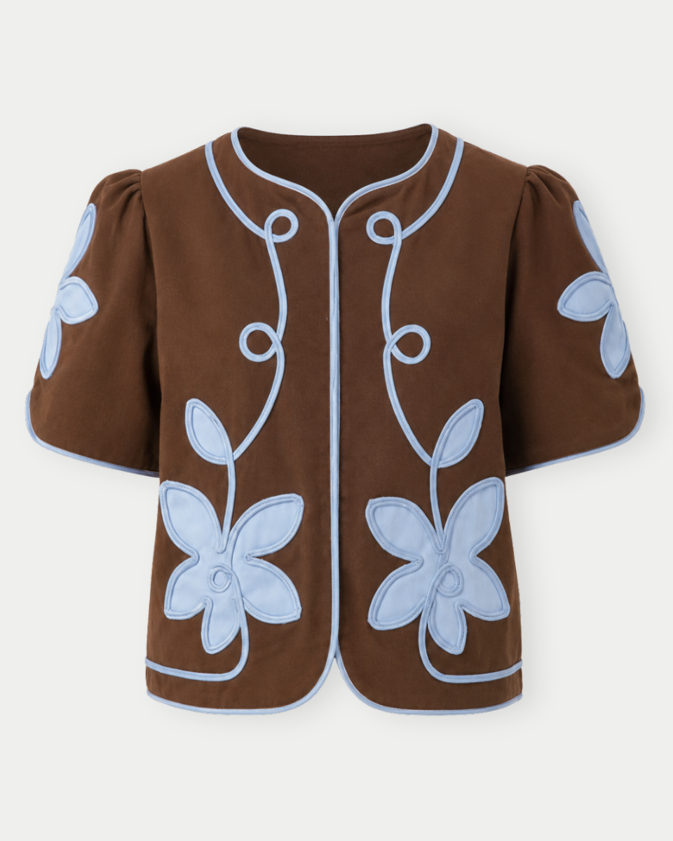 Brown garment with blue floral embroidery on a white background