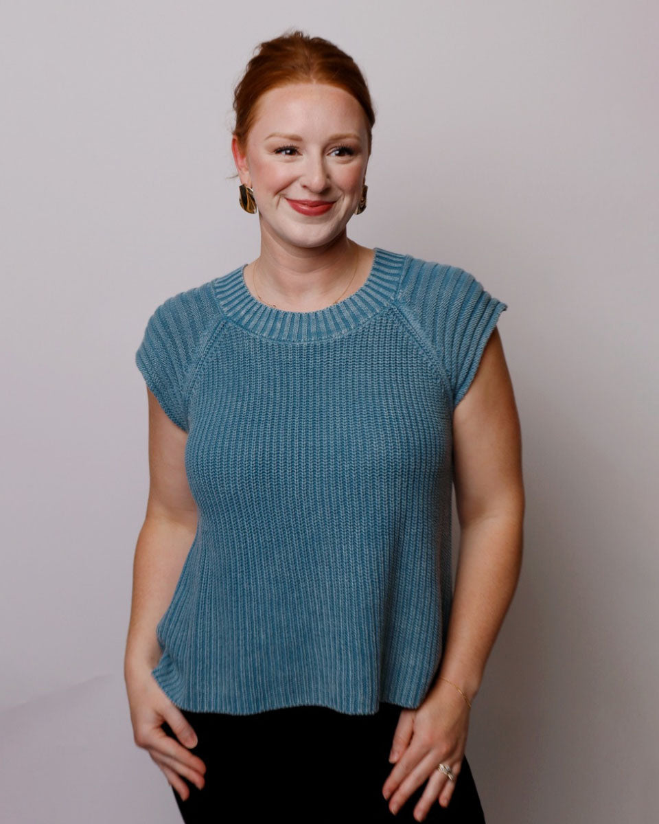 Woman wearing a blue knitted top against a plain background
