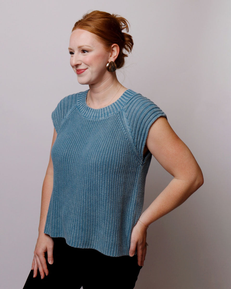 Woman wearing a blue knitted top against a plain background