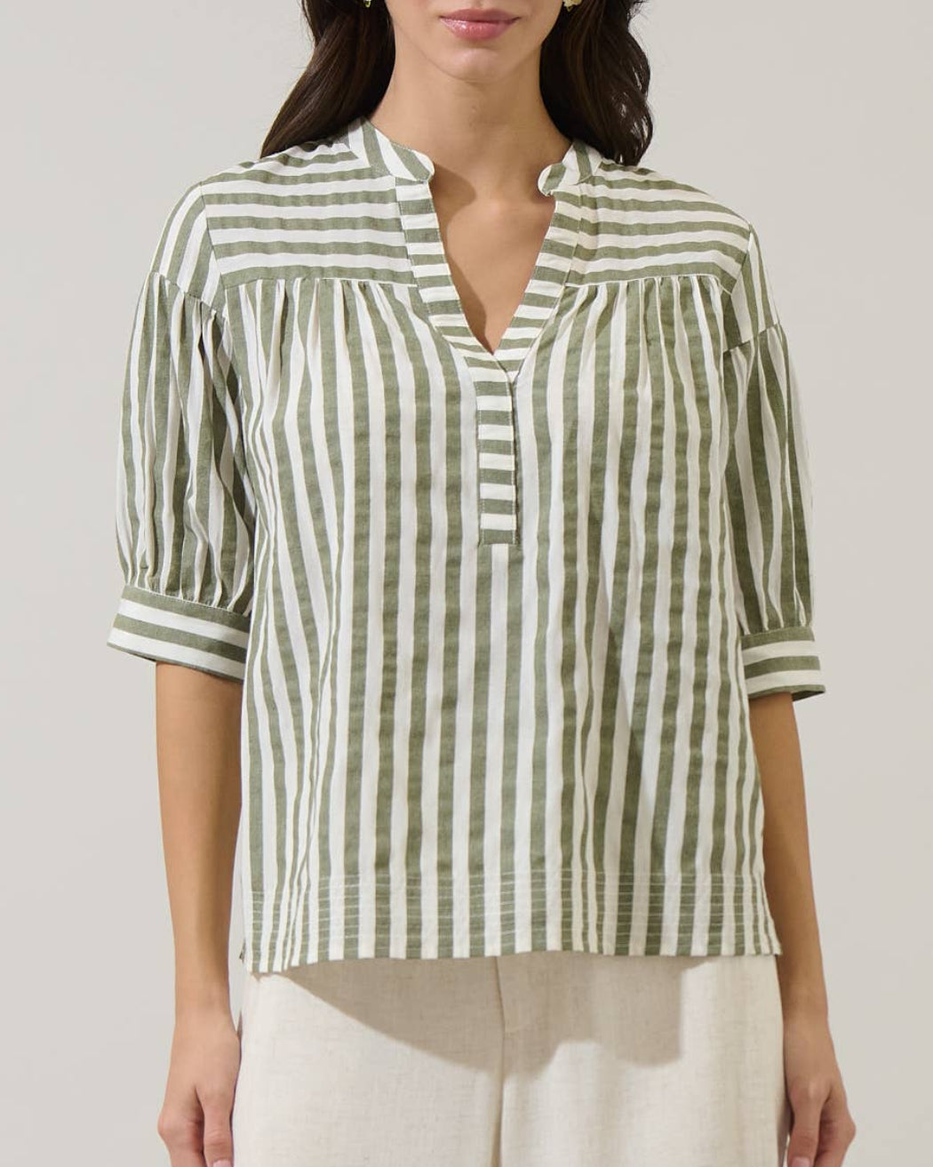 Woman wearing a green and white striped shirt against a plain background