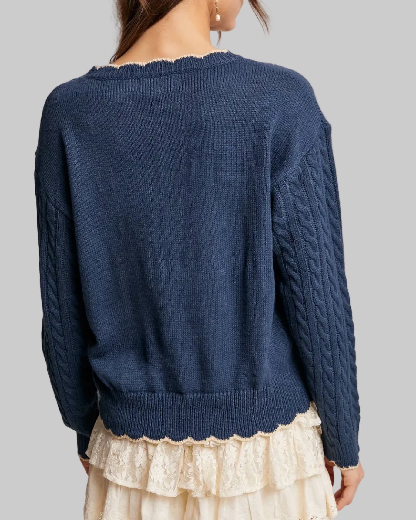 Woman wearing a blue sweater and beige skirt on a plain background