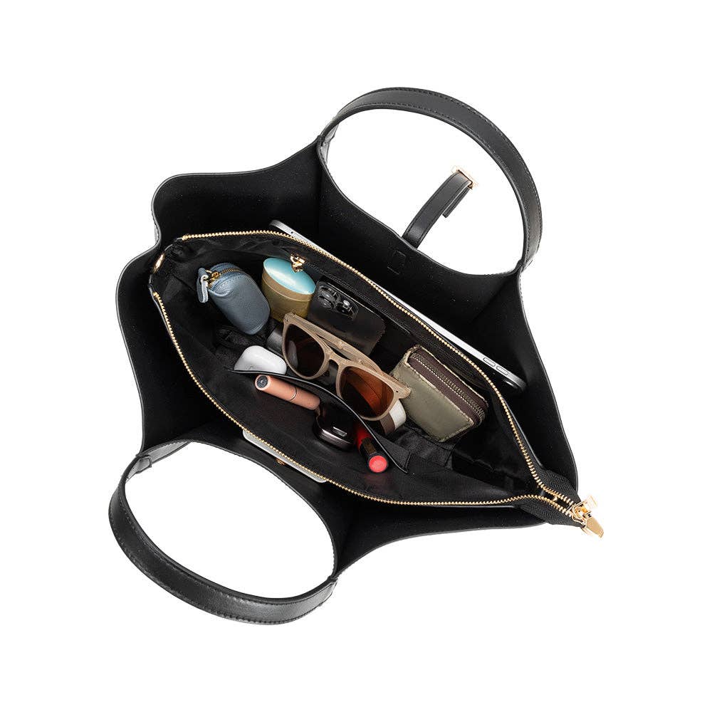 Black handbag with gold zipper open, displaying its contents on a white background