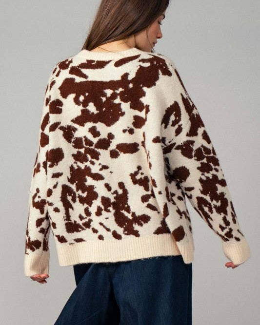 Person wearing a cow print sweater against a gray background