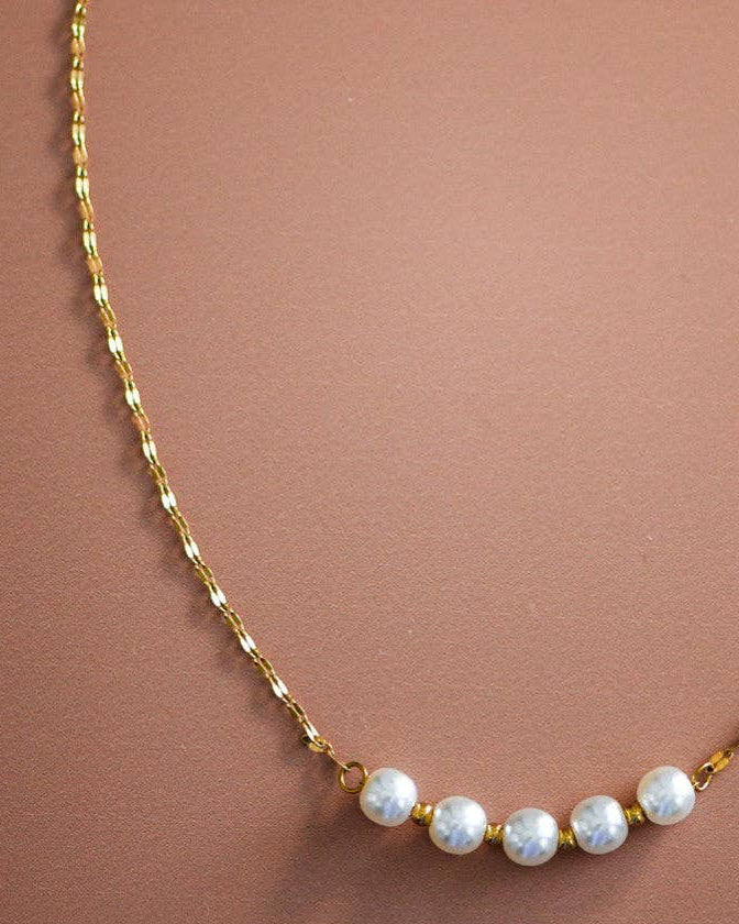 Gold necklace with small pearls on a brown background