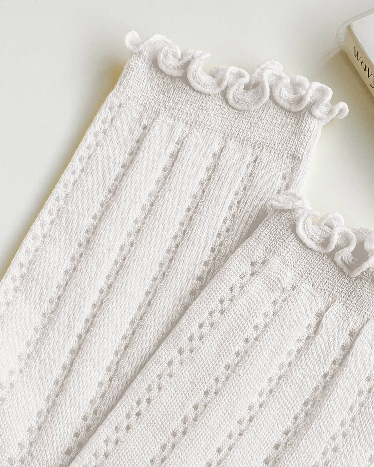 White lace-trimmed fabric with a book titled 'Wavy' in the background