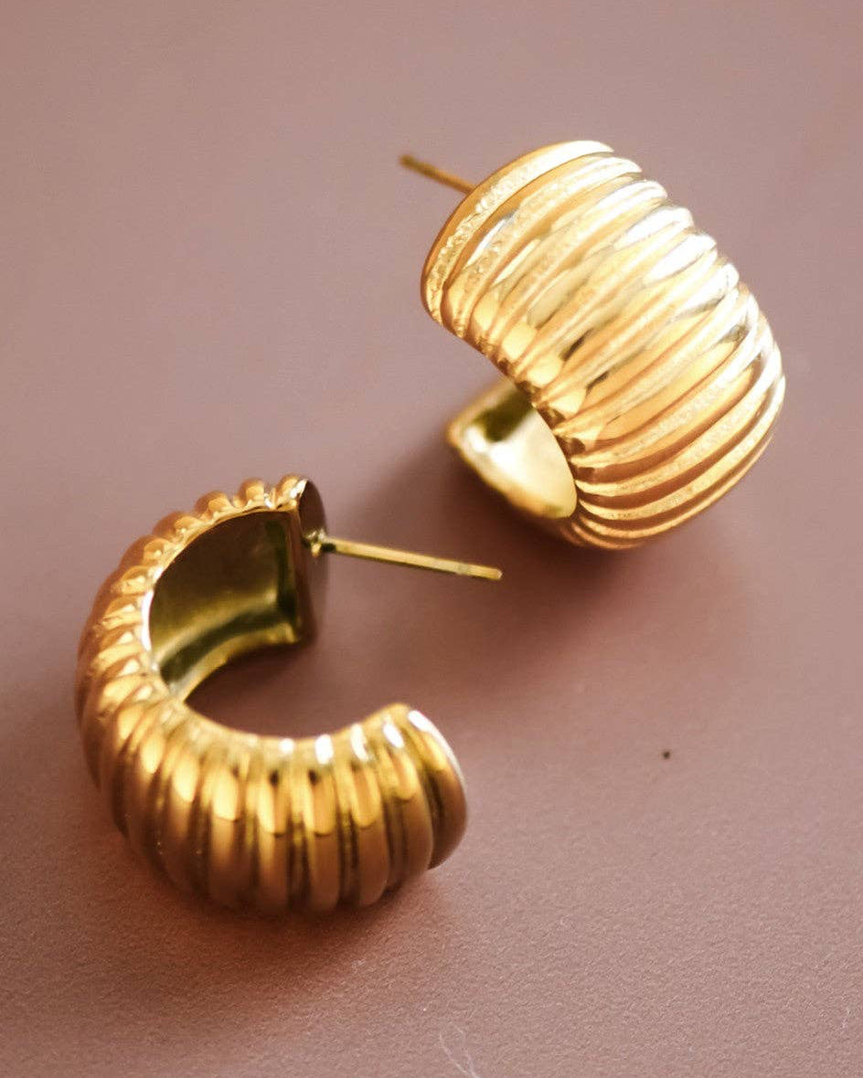 Gold hoop earrings on a pink background