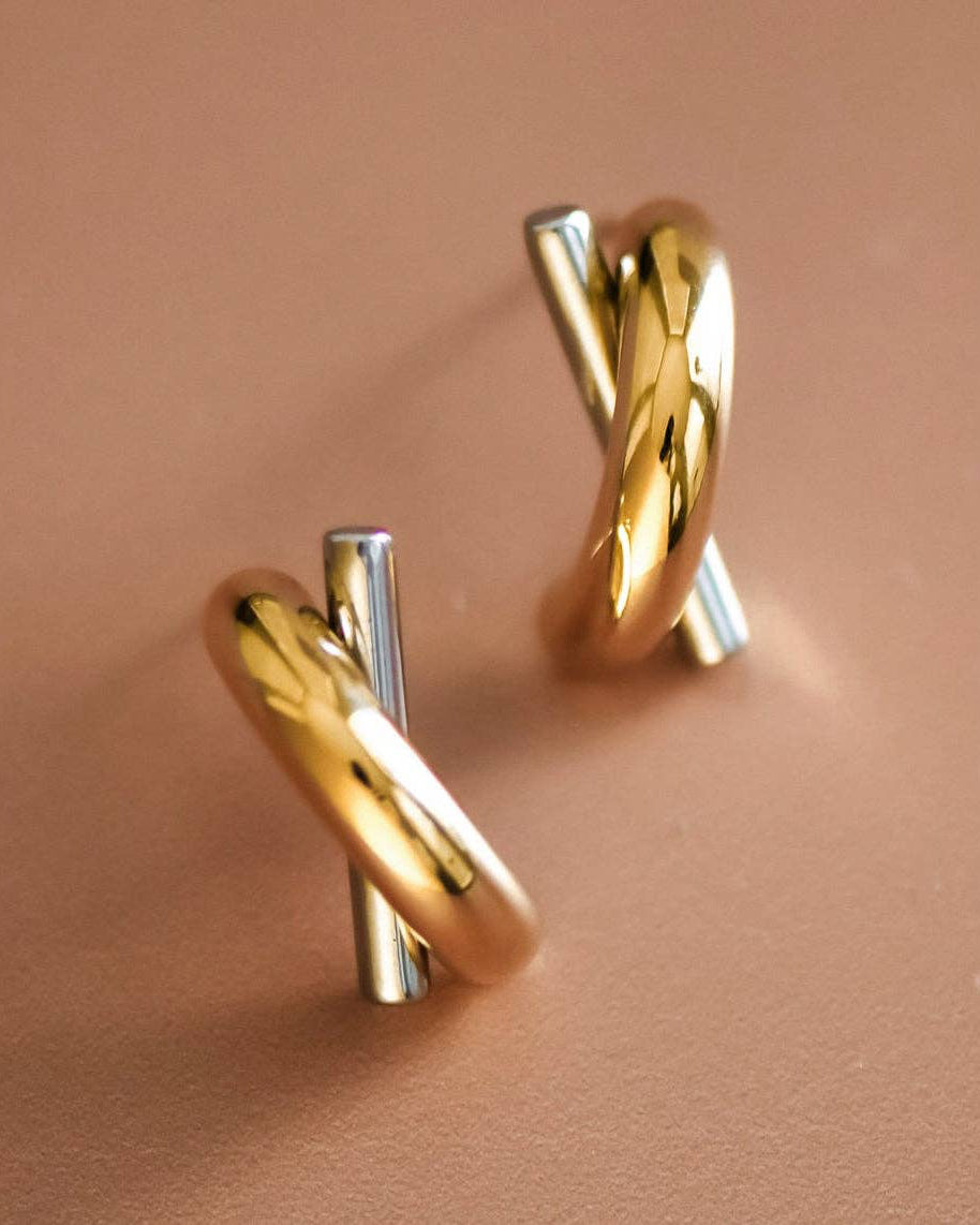 Gold and silver earrings on a pink background