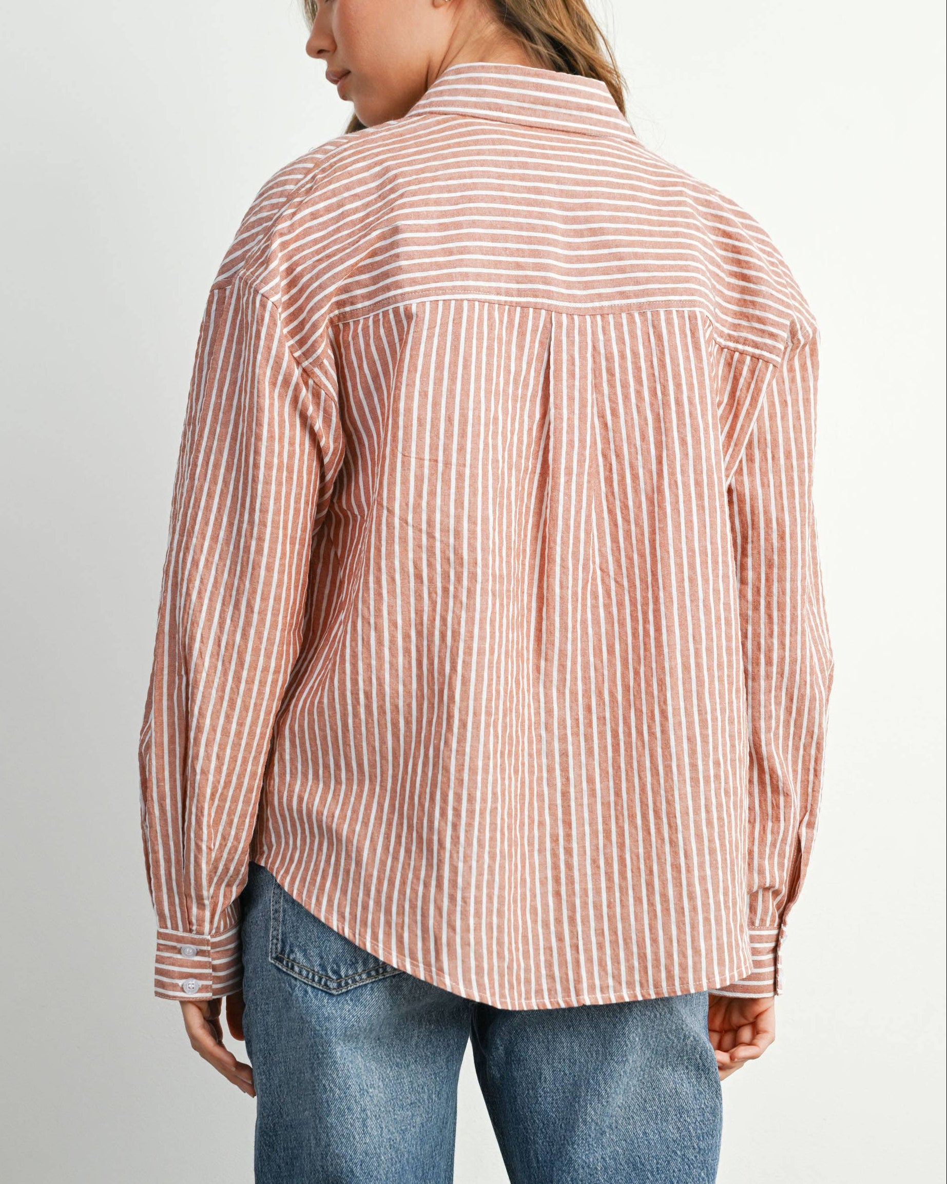 Person wearing a striped shirt and jeans on a plain background