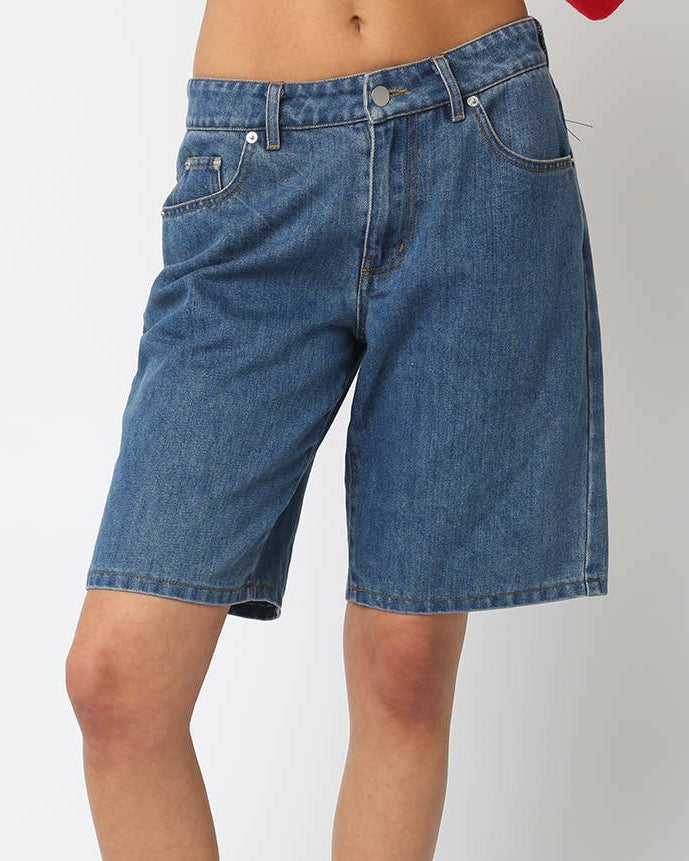 Person wearing blue denim shorts on a white background