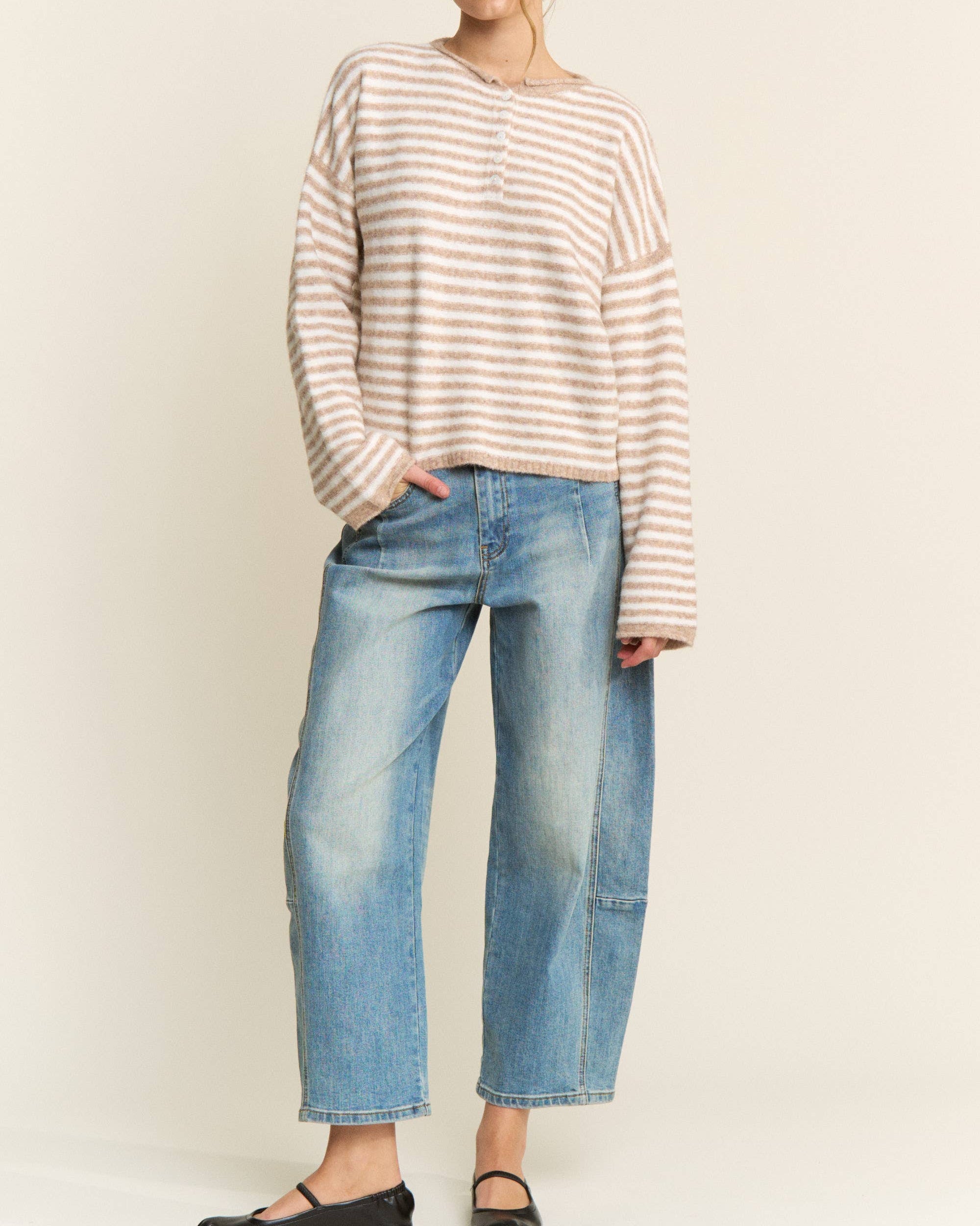 Woman wearing a striped sweater and jeans against a plain background