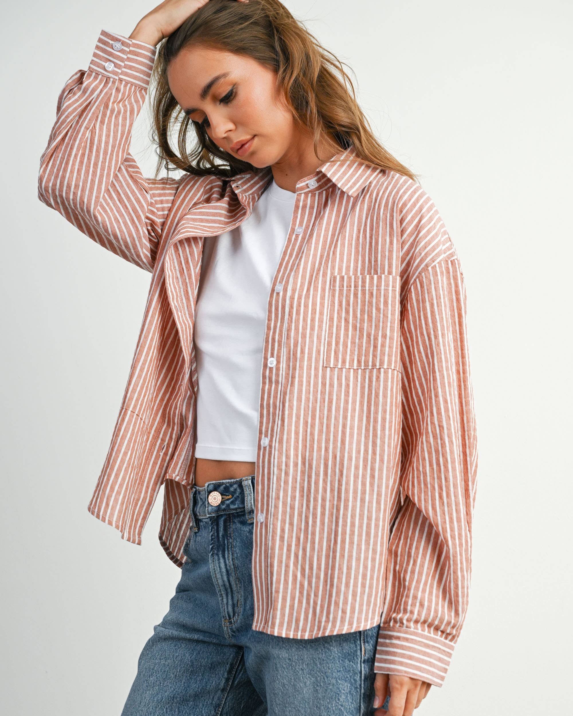 Woman wearing a striped shirt and jeans on a plain background