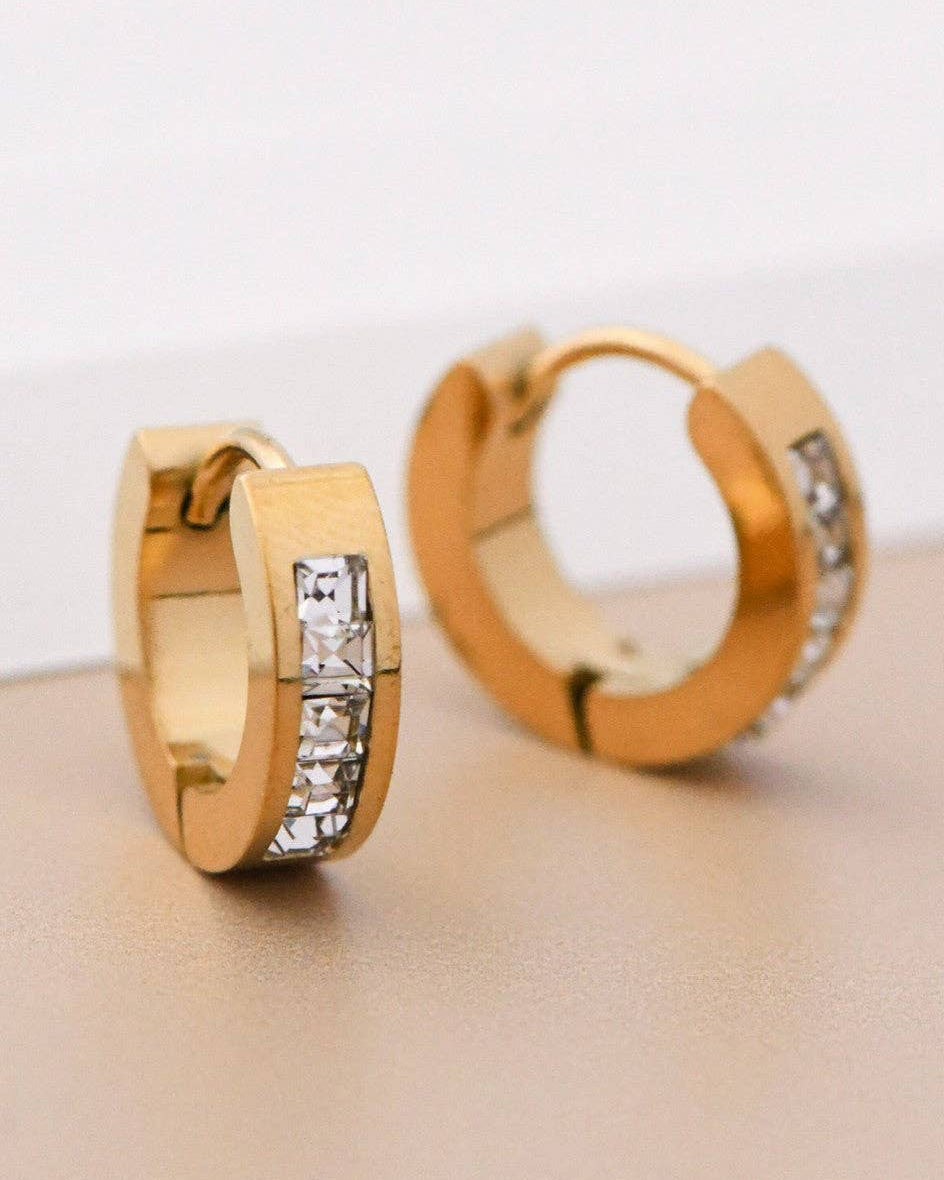 Gold hoop earrings with diamond accents on a light surface
