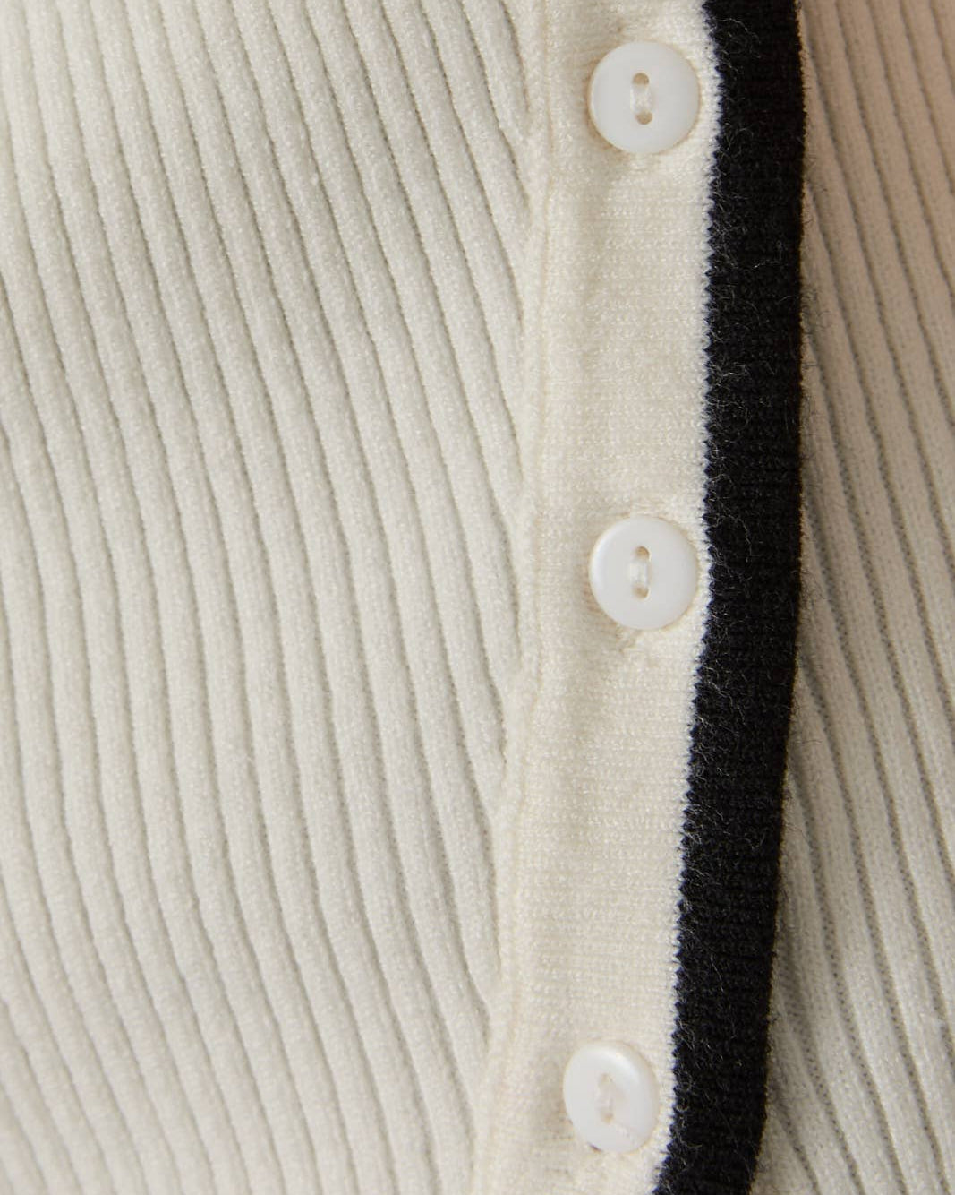 Close-up of a ribbed knit cardigan with button details.