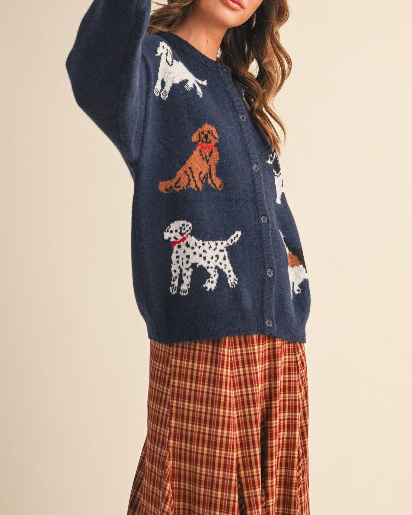 Woman wearing a navy sweater with dog illustrations on a beige background