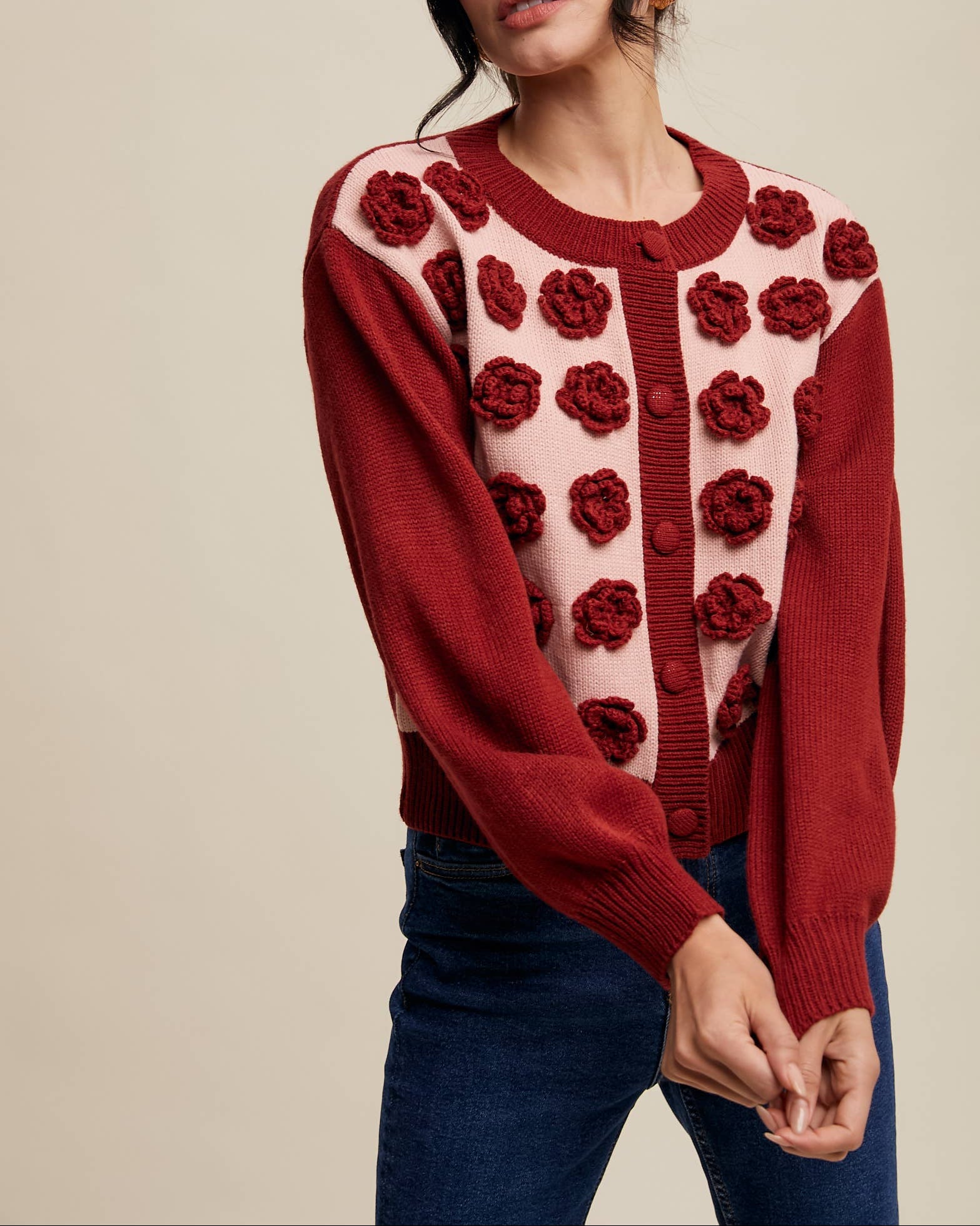 Woman wearing a red sweater with floral patterns on a beige background
