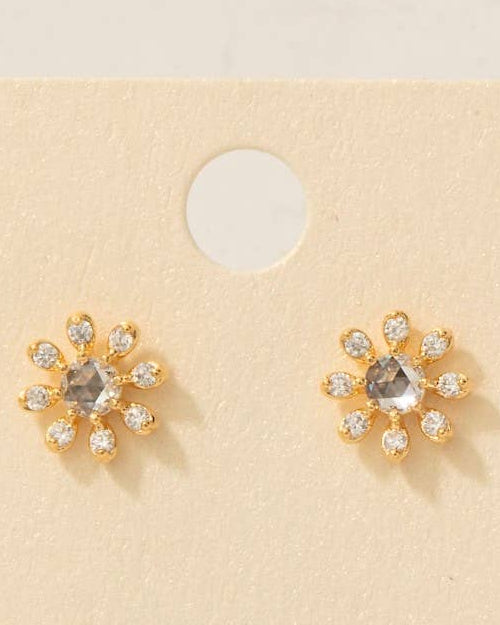 Pair of gold earrings with clear stones on a beige card