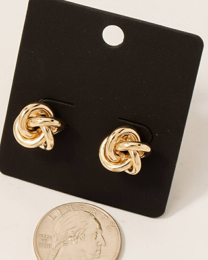 Gold knot earrings on a black card with 'made in Korea' text, next to a US quarter for scale.