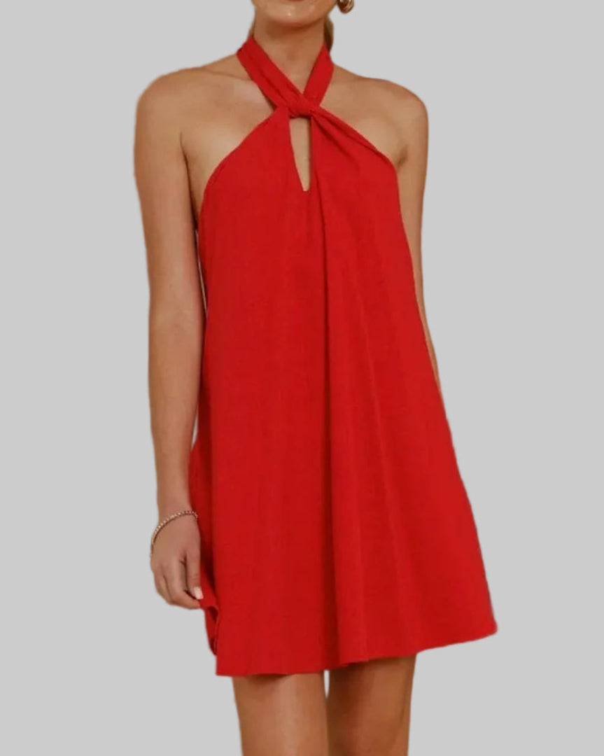 Woman wearing a red dress standing in a room with neutral decor.