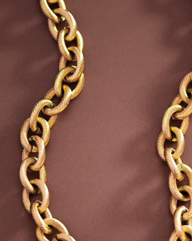 Gold chain necklace on a brown background