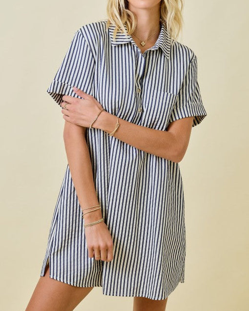Woman wearing a black and white striped dress against a beige background