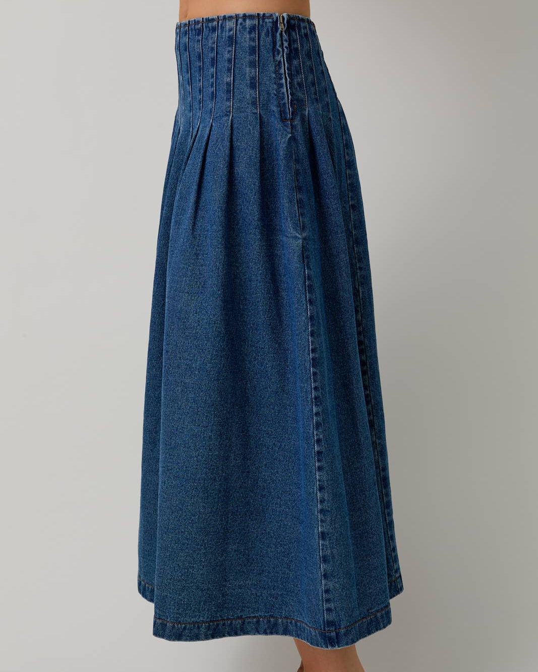Blue denim skirt worn by a person on a plain background