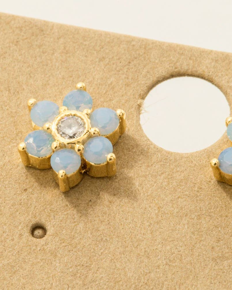 Gold earrings with blue gemstones on a beige card