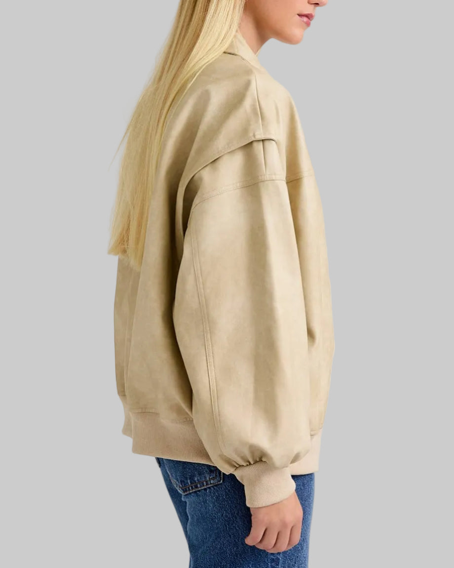 Woman wearing a beige oversized sweatshirt and blue jeans on a plain background