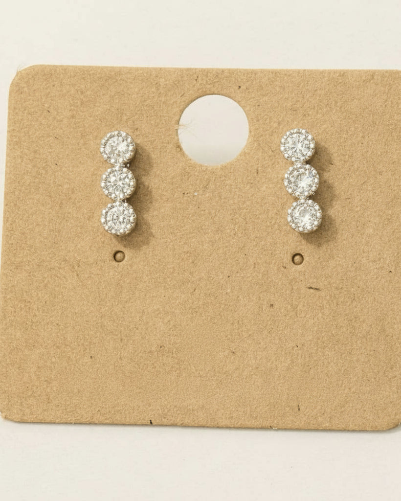 Pair of rhodium-plated earrings on a cardboard backing with 'M' logo.